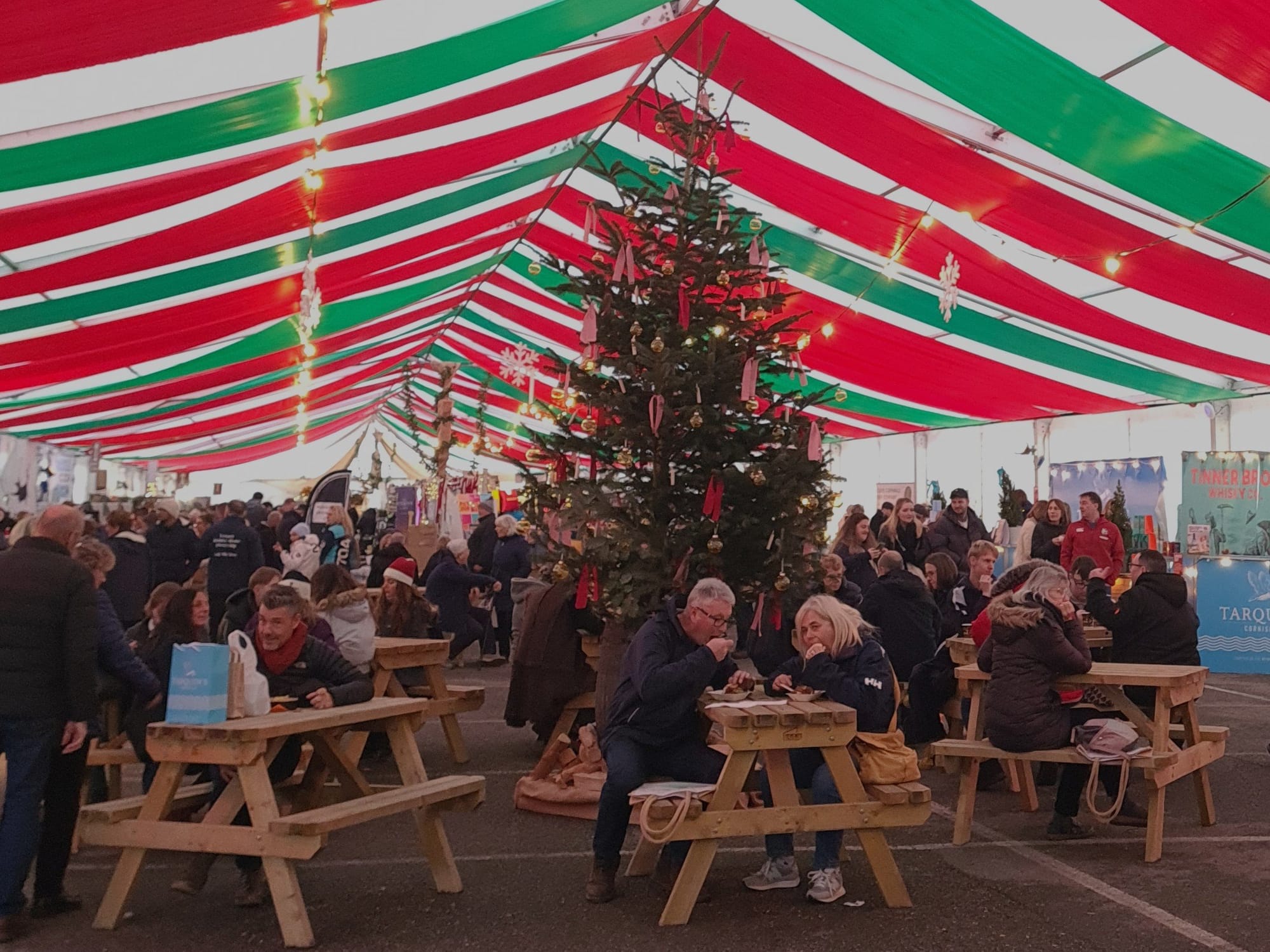 Visitors enjoying food and drink in the Christmas Market tent at Padstow Christmas Fayre
